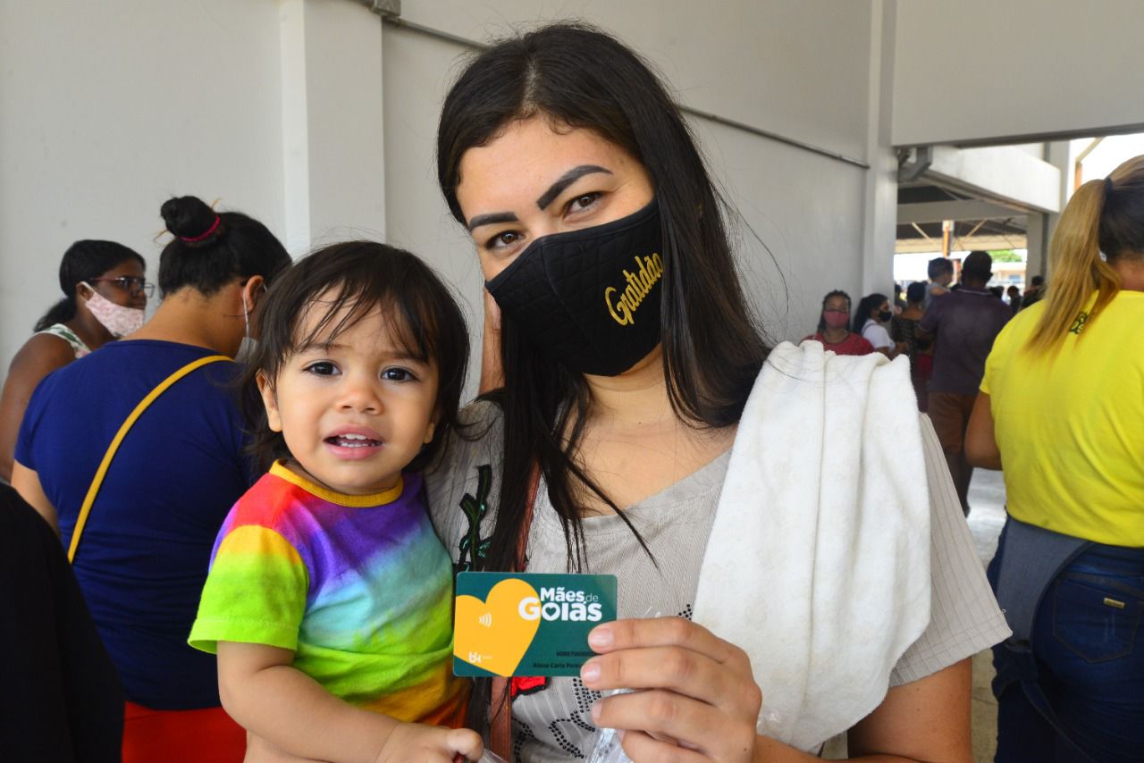 Mulher recebe cartão do programa Mães de Goiás